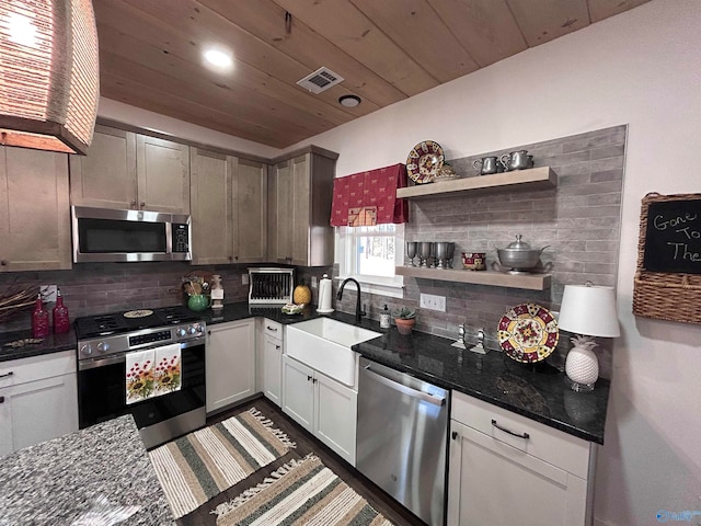 kitchen with sink, tasteful backsplash, dark stone countertops, white cabinets, and appliances with stainless steel finishes