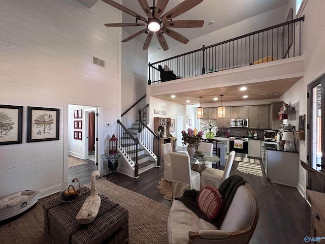 living room with a towering ceiling, dark hardwood / wood-style floors, and ceiling fan