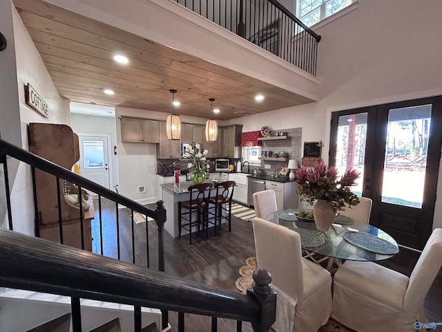 dining room featuring a healthy amount of sunlight, dark hardwood / wood-style flooring, wood ceiling, and a high ceiling