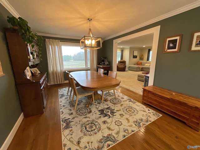 dining room featuring hardwood / wood-style flooring, ornamental molding, and an inviting chandelier