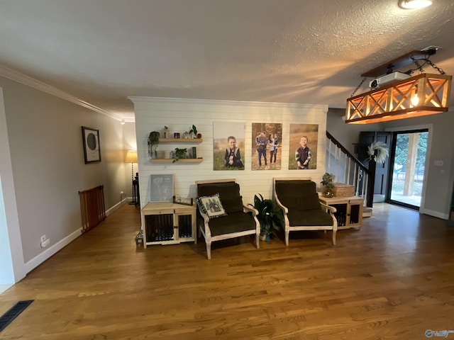 living area featuring ornamental molding, hardwood / wood-style floors, and a textured ceiling