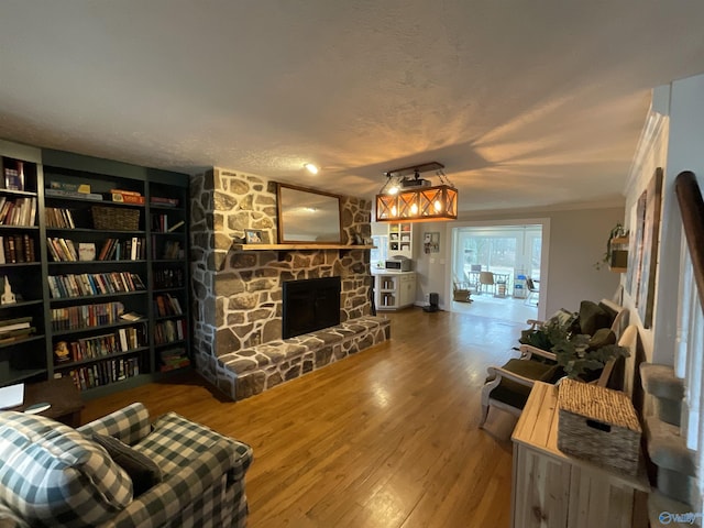 living room featuring a stone fireplace, hardwood / wood-style floors, and a textured ceiling