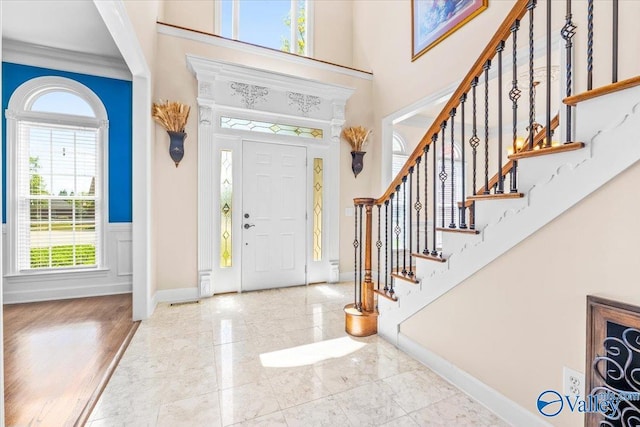 entryway with crown molding and a towering ceiling