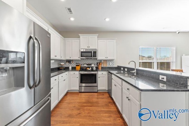 kitchen with stainless steel appliances, kitchen peninsula, sink, and white cabinets