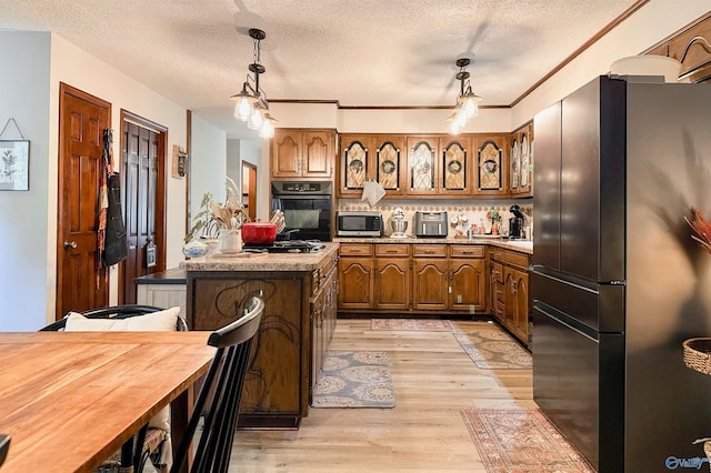 3103 Burningtree Mountain Rd, Decatur, AL 35603 - kitchen with freestanding refrigerator, black oven, stainless steel microwave, brown cabinets, and a textured ceiling