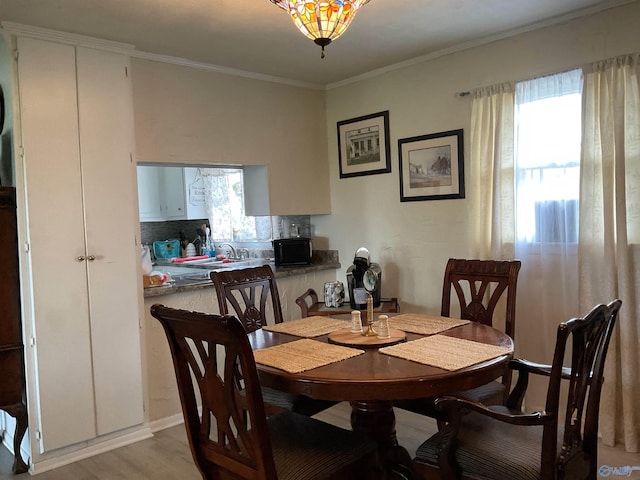dining space with plenty of natural light, light wood-style flooring, and crown molding