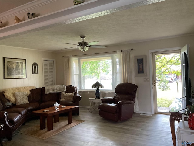 living room with crown molding, a ceiling fan, visible vents, and wood finished floors