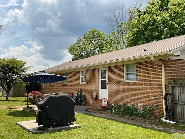 rear view of house featuring a lawn, brick siding, and metal roof
