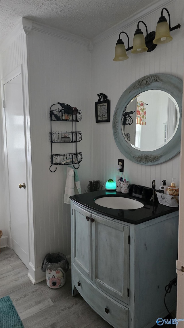 bathroom featuring a textured ceiling, ornamental molding, wood finished floors, and vanity