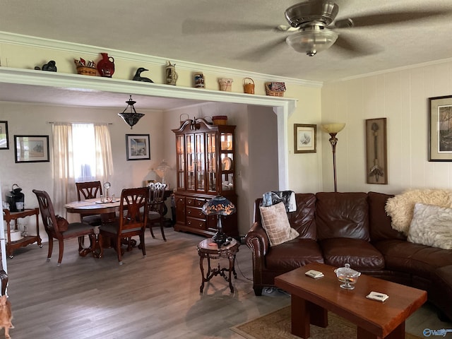 living room with crown molding, a ceiling fan, and wood finished floors