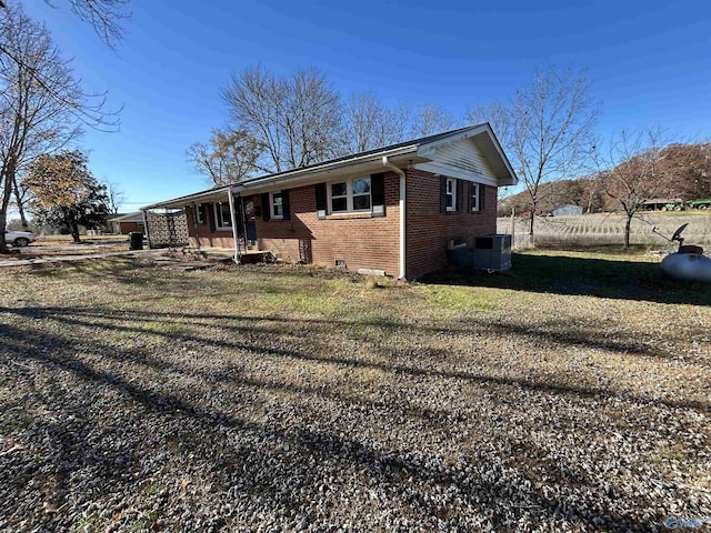 exterior space featuring central AC unit and a front lawn