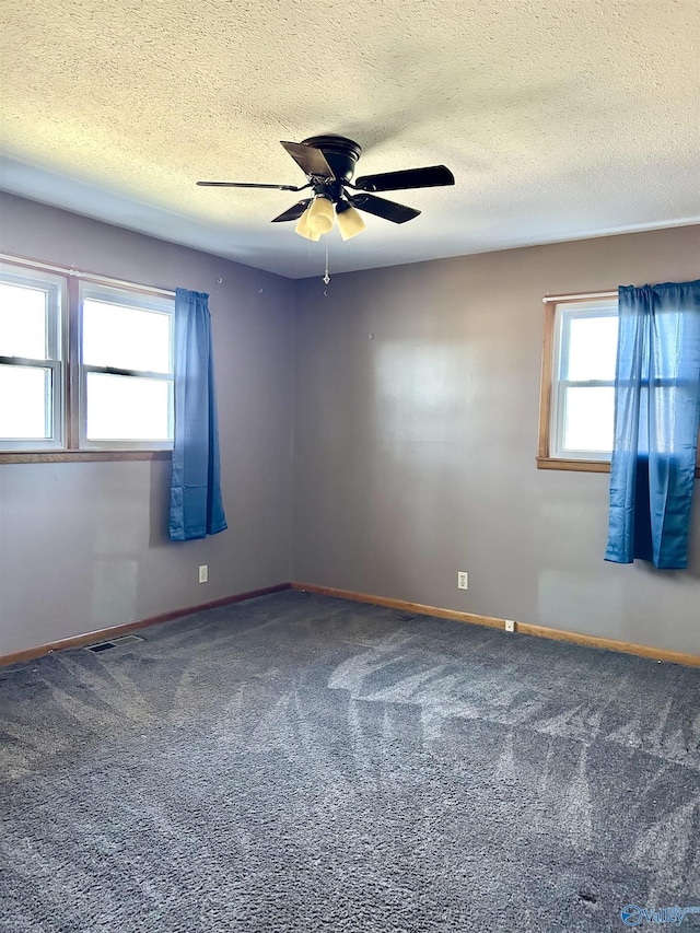 carpeted spare room with ceiling fan, plenty of natural light, and a textured ceiling