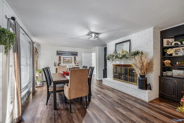 dining room with dark hardwood / wood-style floors, ornamental molding, and a brick fireplace