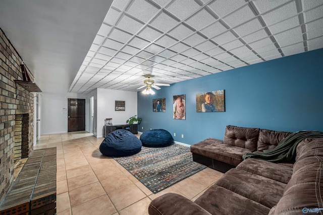 tiled living room featuring ceiling fan and a brick fireplace