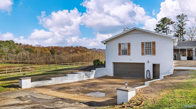 view of property exterior with central AC unit, a rural view, and a garage