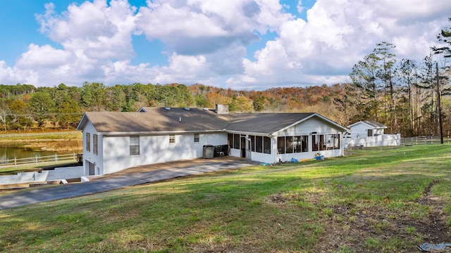 back of property featuring a sunroom, a water view, a yard, central AC, and a garage