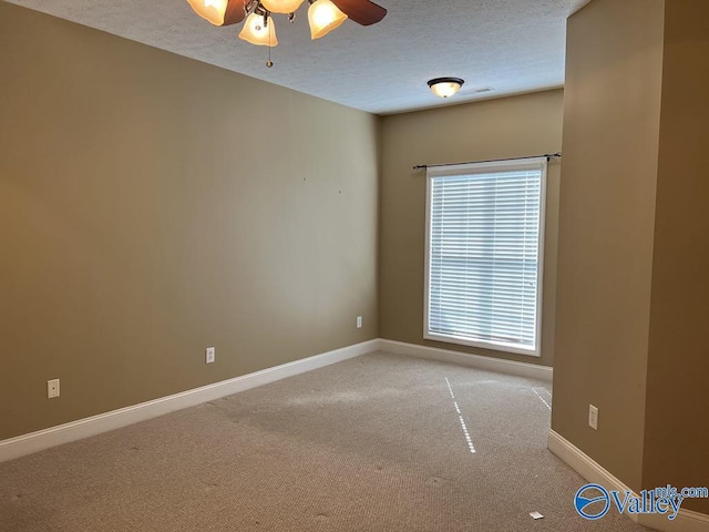 spare room with a ceiling fan, light carpet, a textured ceiling, and baseboards