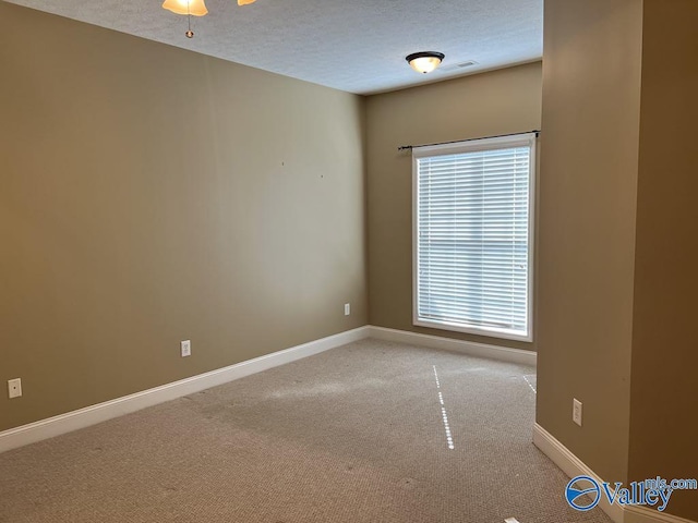 unfurnished room with carpet floors, visible vents, baseboards, and a textured ceiling