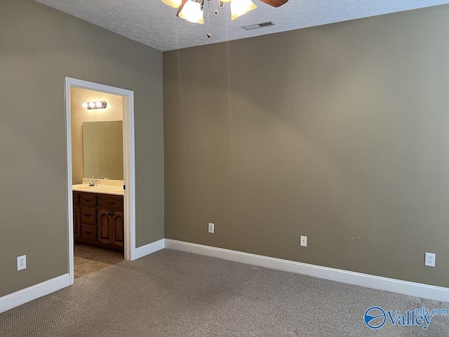 unfurnished bedroom featuring a textured ceiling, light carpet, a sink, visible vents, and baseboards