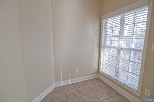 empty room with baseboards and light tile patterned floors