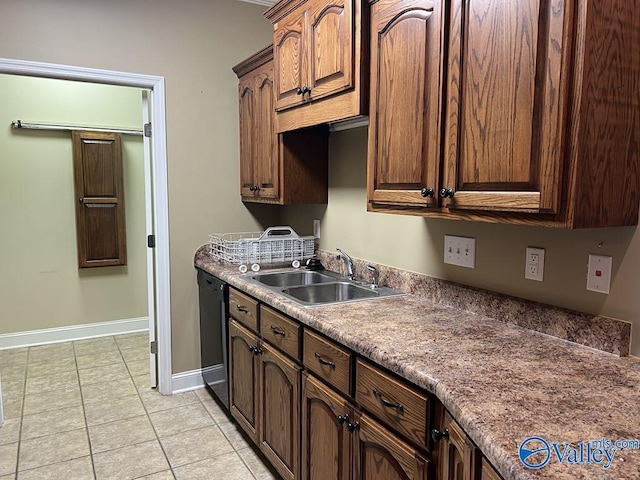 kitchen featuring light tile patterned floors, a sink, baseboards, dishwasher, and dark countertops