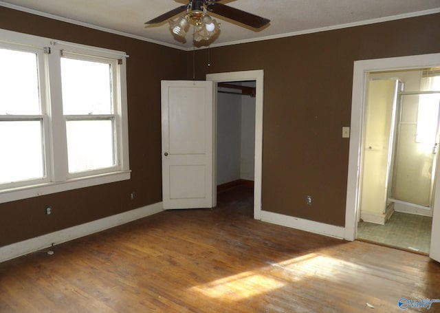 unfurnished bedroom featuring crown molding, baseboards, and wood finished floors