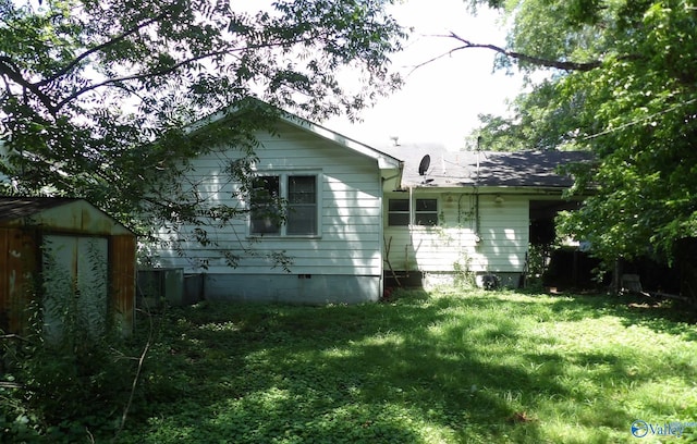 view of side of home with a yard, an outdoor structure, a storage shed, and central AC unit