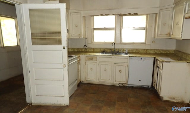 kitchen featuring white dishwasher, stove, light countertops, and a sink