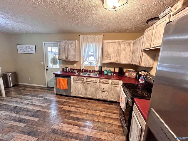 kitchen with stainless steel appliances, sink, light brown cabinetry, dark hardwood / wood-style floors, and a textured ceiling