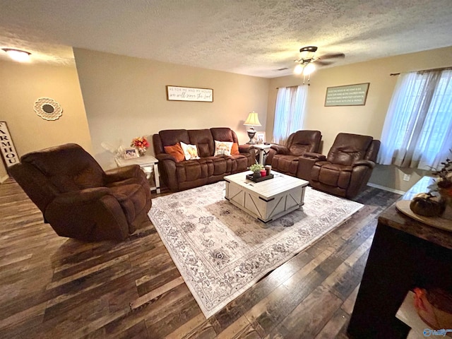 living room featuring dark wood-type flooring, a textured ceiling, and ceiling fan