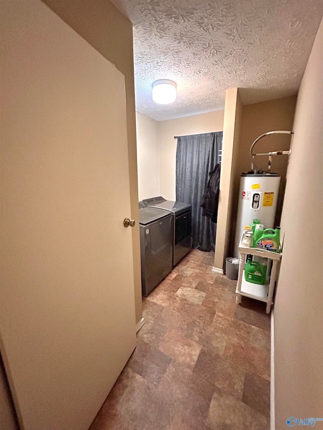 washroom with water heater, a textured ceiling, and washer and clothes dryer