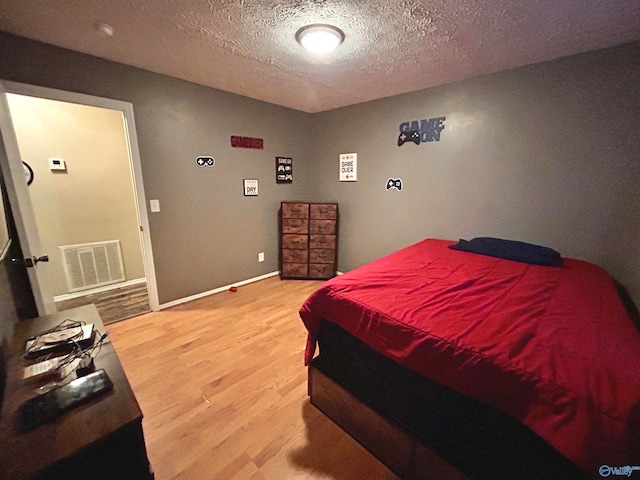 bedroom with a textured ceiling and hardwood / wood-style flooring