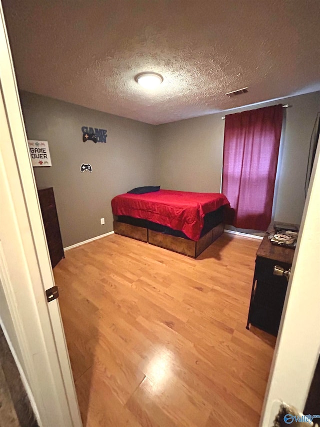 bedroom with hardwood / wood-style flooring and a textured ceiling