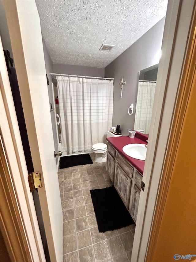 bathroom featuring vanity, a textured ceiling, and toilet