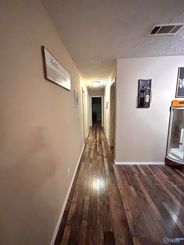 corridor with dark wood-type flooring and a textured ceiling