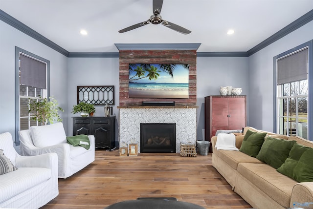 living room featuring hardwood / wood-style floors, a fireplace, ornamental molding, and ceiling fan