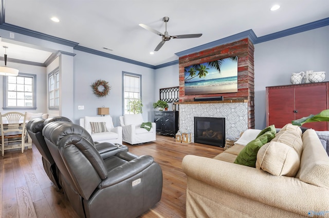 living room with ornamental molding, hardwood / wood-style floors, ceiling fan, and a fireplace