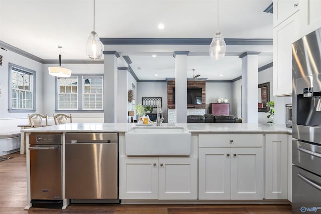 kitchen featuring decorative light fixtures, white cabinetry, sink, ornamental molding, and light stone counters