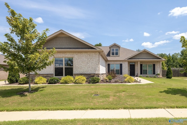 craftsman-style house with stone siding, a front lawn, and fence