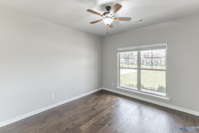 empty room featuring dark wood-style floors, visible vents, a ceiling fan, and baseboards