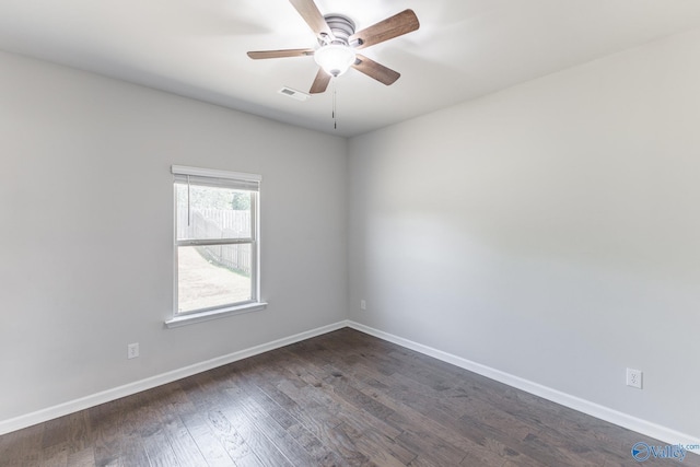 spare room featuring a ceiling fan, visible vents, dark wood-style floors, and baseboards