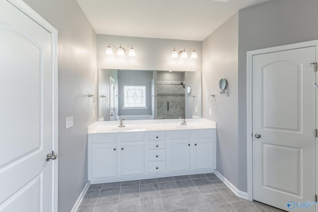 full bath with a tile shower, double vanity, baseboards, and a sink