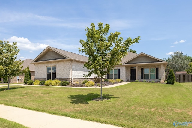 view of front of house featuring brick siding, a front lawn, and fence