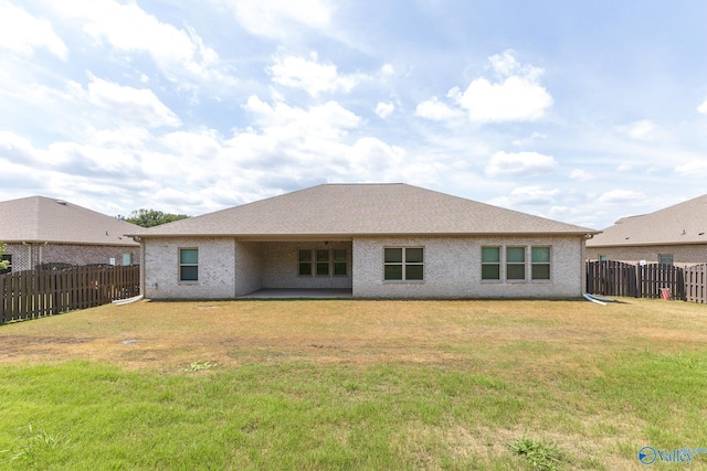 rear view of house with a yard, brick siding, and a fenced backyard