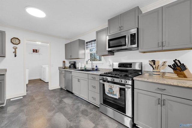 kitchen featuring gray cabinetry, sink, ornamental molding, separate washer and dryer, and stainless steel appliances