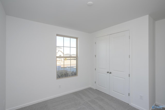 unfurnished bedroom with a closet and light colored carpet