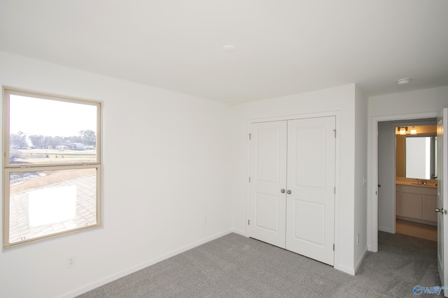 unfurnished bedroom with light carpet, a closet, and sink