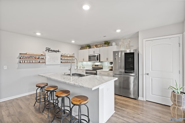 117 Hank Ct, Hazel Green, AL 35750 - kitchen featuring stainless steel appliances, a breakfast bar, white cabinetry, light wood-style floors, and recessed lighting