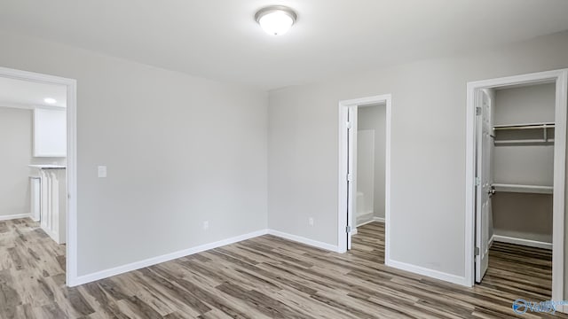 unfurnished bedroom with a spacious closet, a closet, and light wood-type flooring