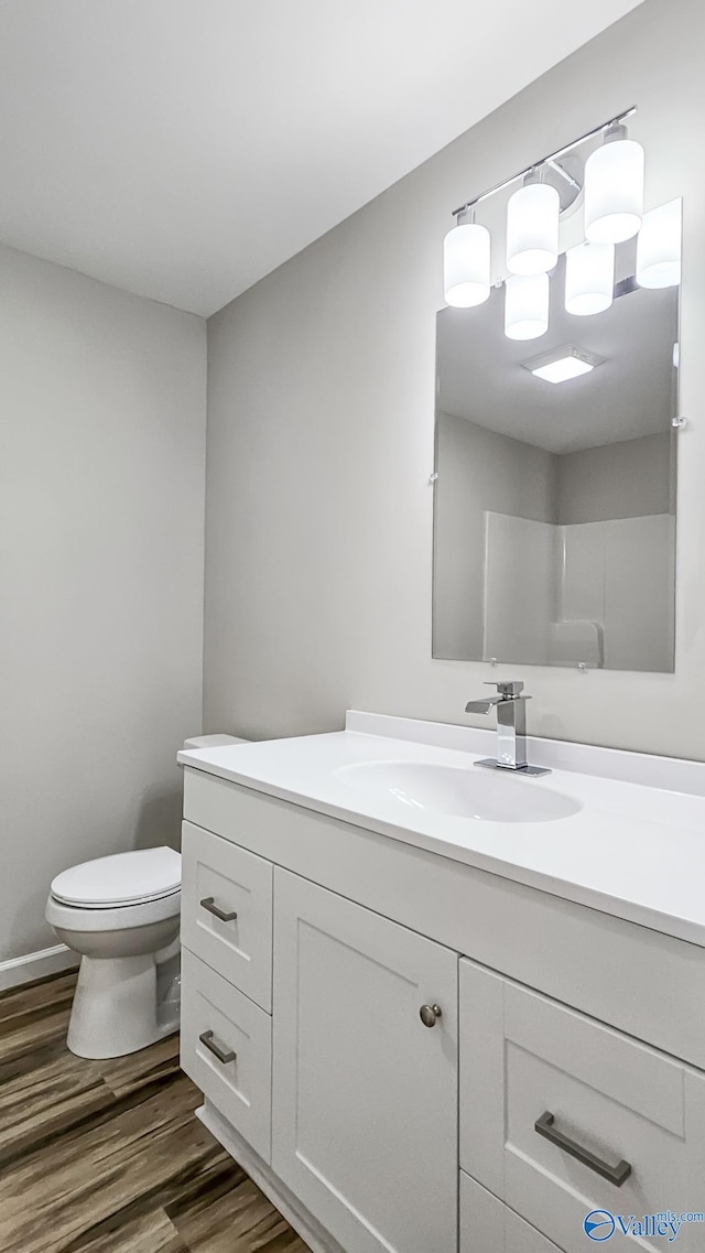 bathroom featuring hardwood / wood-style flooring, vanity, toilet, and a shower